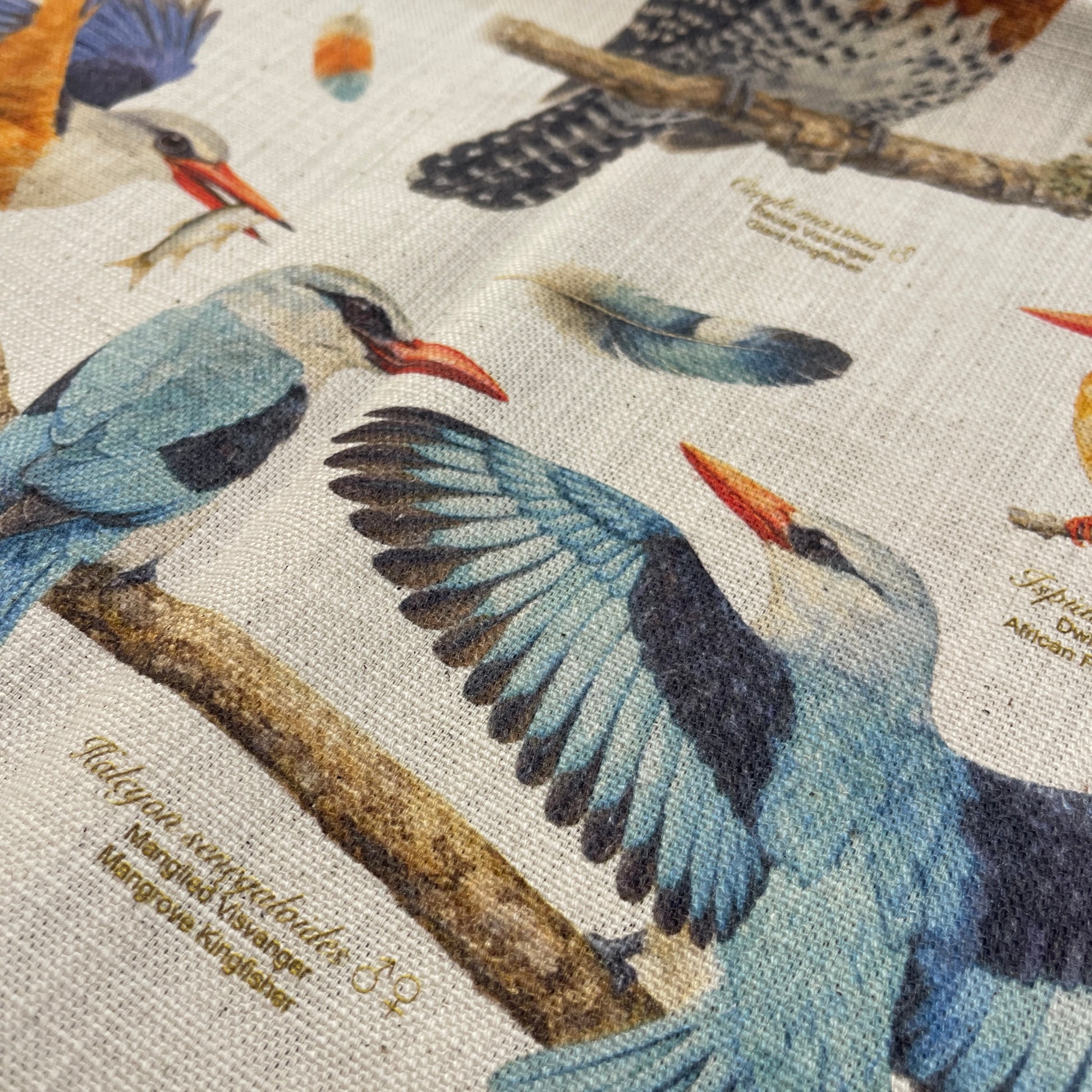 Close-up of a fabric with detailed illustrations of birds on branches.